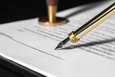 Karanlık masada dolma kalemle belge imzalıyorum, yakın plan. Noter sözleşmesi