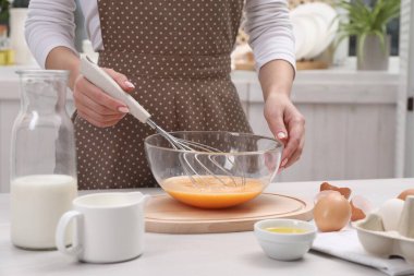 Kadın kasede yumurta çırpıyor, kapalı bir masada, yakın plan.