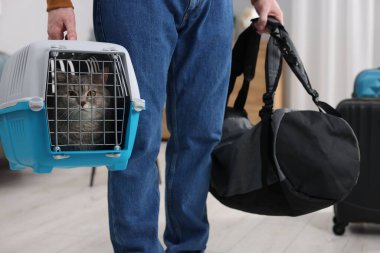 Evcil hayvanla seyahat et. Şirin kedisi ve çantası olan bir adam eve yakın çekim yapıyor.