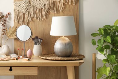 Aynalı giyinme masası, makyaj malzemeleri ve dekoru odada.