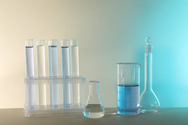 Laboratuvar analizi. Masada renk arkaplanına karşı farklı cam eşyalar