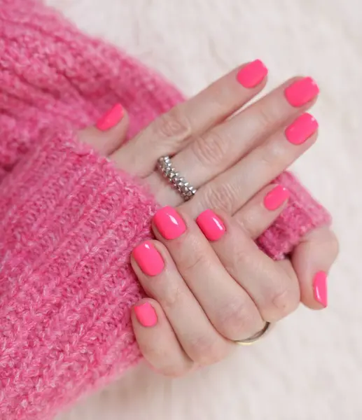 Woman showing her manicured hands with pink nail polish on faux fur mat, closeup