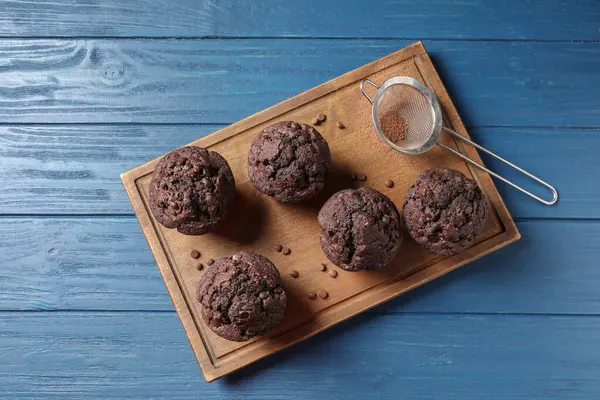 Köstliche Schokoladenmuffins Und Sieb Mit Kakaopulver Auf Blauem Holztisch Draufsicht — Stockfoto