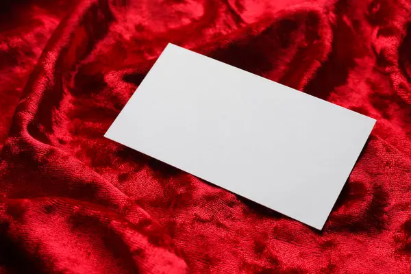 Blank business card on red fabric, closeup. Mockup for design