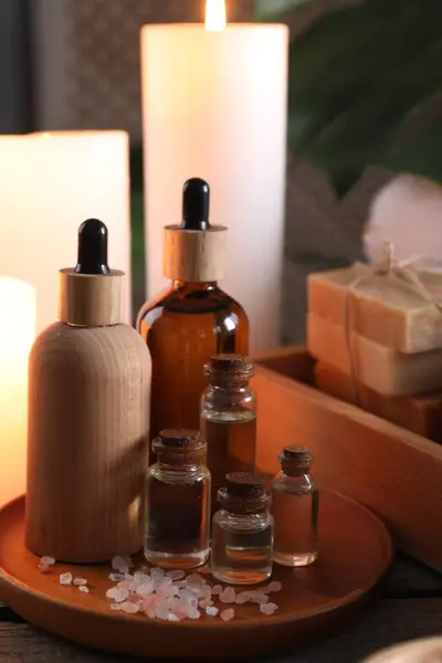 Spa composition. Bottles of cosmetic products and sea salt on wooden table
