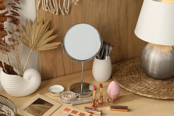 Dressing table with mirror and makeup products in room