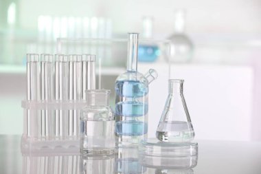 Laboratuvar analizi. Kapalı alandaki beyaz masa üzerinde sıvı bulunan farklı camlar.