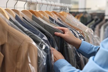 Kuru temizleme servisi. Kadın plastik torba içinde ceketini alıyor, kapalı mekandan, yakın plan.