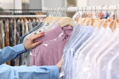 Kuru temizleme servisi. Kadın gömleğini plastik torbaya koyuyor, kapalı mekandan, yakın plan.