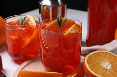 Aperol spritz kokteyli, biberiye ve portakal dilimleri beyaz masada, yakın plan.