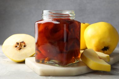 Kavanozda ev yapımı ayva reçeli ve gri desenli masada meyveler. Yakın plan.