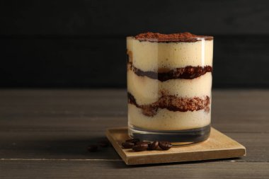 Bardakta nefis tiramisu ve ahşap masada kahve çekirdekleri, yakın plan. Metin için boşluk