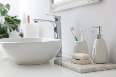 Lavabonun yanında banyo aksesuarları ve kişisel bakım ürünleri var.