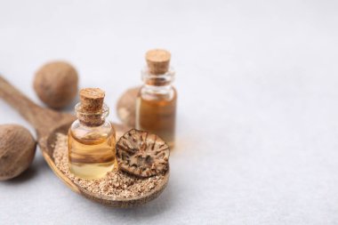Nutmeg 'in temel yağı ve kaşığı. Işık masasında yer fıstığı var. Yakın plan. Metin için boşluk