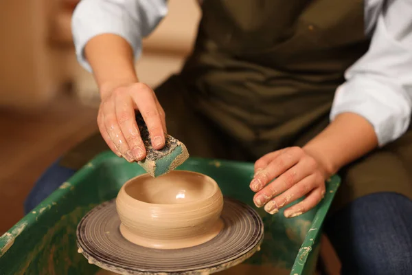 Clay crafting. Woman making bowl on potter\'s wheel indoors, closeup