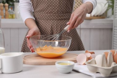 Kadın kasede yumurta çırpıyor, kapalı bir masada, yakın plan.