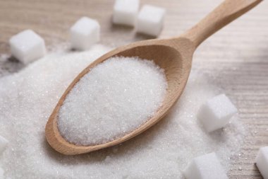 Masada farklı türde beyaz şeker ve kaşık, yakın plan.