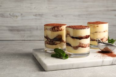 Bardakta nefis tiramisu, nane ve elek, gri desenli masada kakao tozu. Metin için boşluk