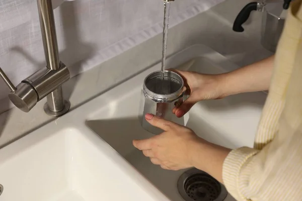 Woman washing moka pot at sink in kitchen, closeup
