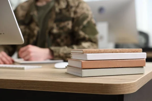 Military education. Student in soldier uniform learning at wooden table indoors, selective focus