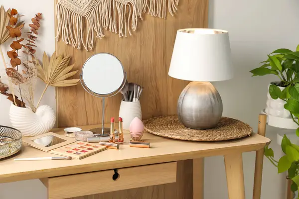 Dressing table with mirror, makeup products and decor in room
