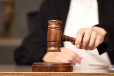 Yargıç, mahkeme salonundaki ahşap masaya tokmak vuruyor, yakın plan.