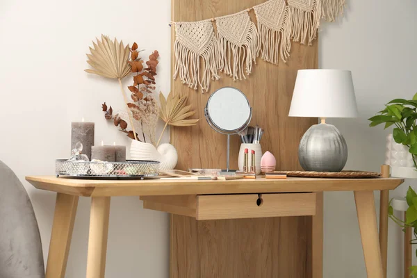 Dressing table with mirror, makeup products and decor in room