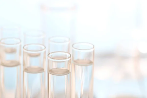 Laboratory analysis. Many glass test tubes on blurred background, closeup and space for text