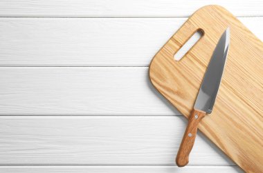 Beyaz ahşap masada keskin bir bıçak, üst manzara. Metin için boşluk