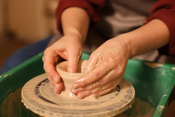 Woman crafting with clay on potter\'s wheel indoors, closeup