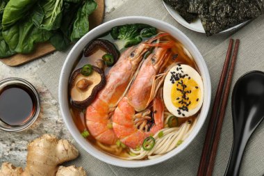 Gri desenli masada servis edilen karides ve yumurtalı ramen. Erişte çorbası.