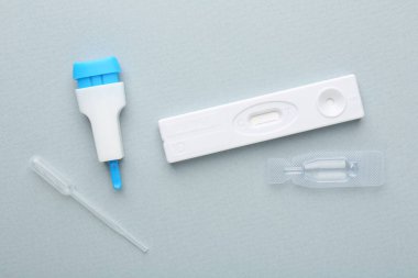 Açık mavi arkaplan üzerinde tek kullanımlık ekspres test kiti, düz yatıyordu