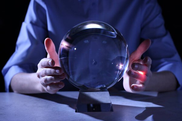 Бизнесмен, использующая мяч, чтобы предсказать будущее за столом крупным планом
