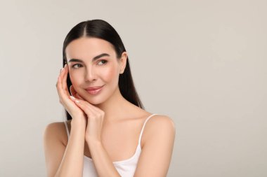 Gri arka planda sağlıklı cildi olan güzel bir kadın.