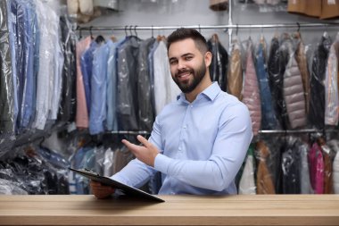 Kuru temizleme servisi. Kapalı alanda pano tutan mutlu işçi.