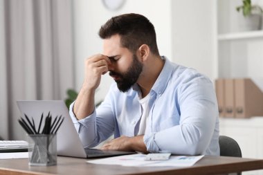İş yerinde baş ağrısı çeken bir adam.