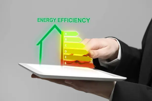 Energy efficiency rating coming out of tablet. Man using device on light background, closeup
