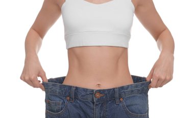 Beyaz arka planda büyük kot giyen zayıf kadın, yakın plan. Kilo kaybı