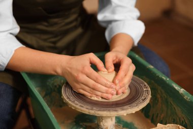 Çömlekçinin çarkında çamurla el işi yapan kadın, yakın plan.