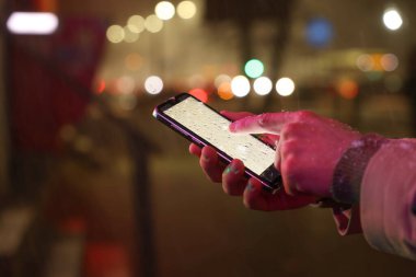 Gece caddesinde akıllı telefon kullanan bir adam, yakın plan. Metin için boşluk