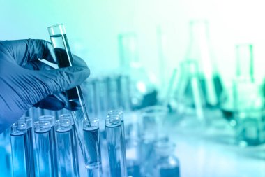 Test tüpü tutan laboratuvar çalışanı, yakın plan. Renk tonlu