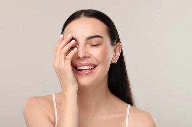 Gri arka planda sağlıklı ciltli güzel bir kadın.