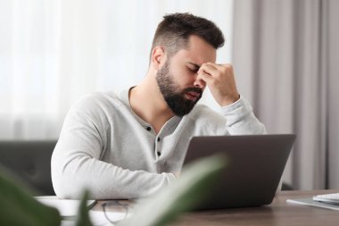 İş yerinde baş ağrısı çeken bir adam.