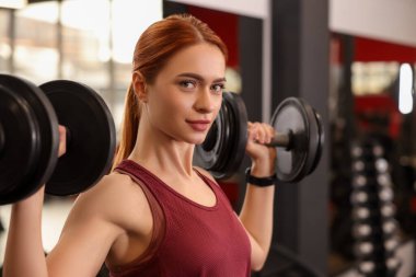 Spor salonunda halter eğitimi almış atletik bir genç kadın.