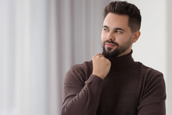Handsome man in stylish sweater indoors, space for text