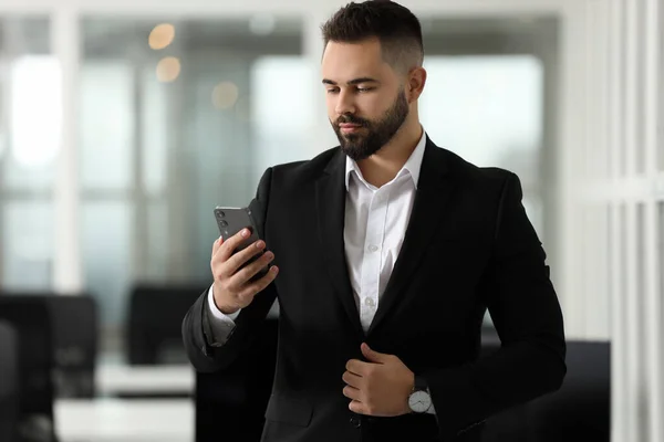 Handsome man with smartphone in office. Lawyer, businessman, accountant or manager