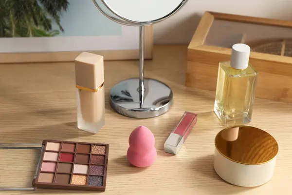 Makeup products and perfume on wooden dressing table