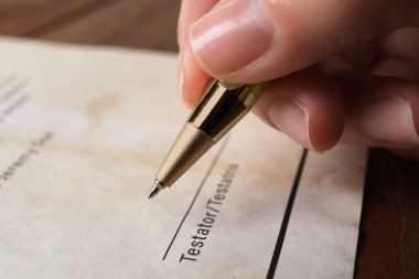 Woman signing Last Will and Testament at table, closeup clipart