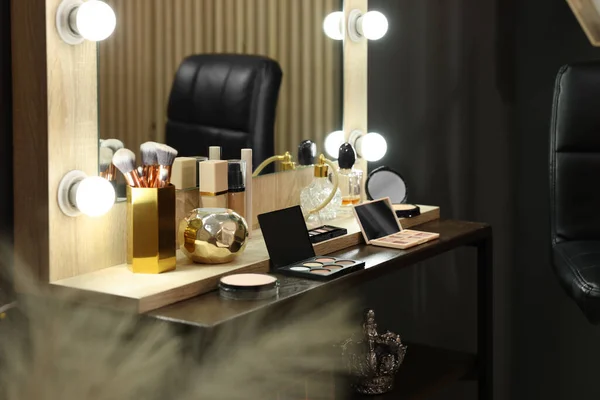 Makeup room. Stylish mirror with light bulbs and beauty products on dressing table indoors
