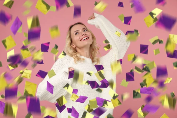 Happy woman under falling confetti on pink background